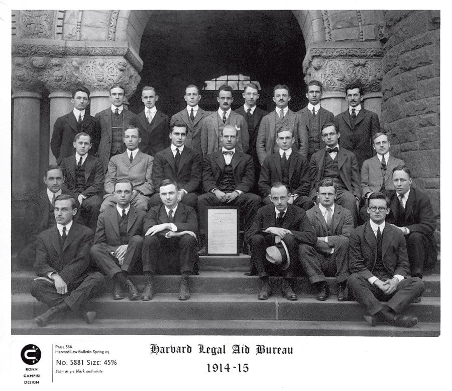 Group of men sitting in front of building in 1914