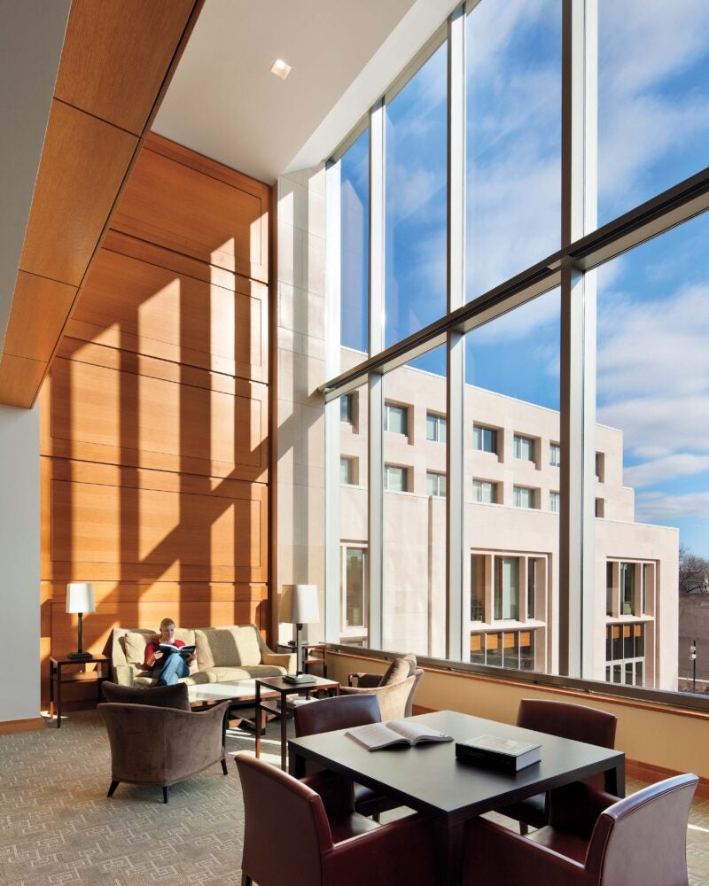 Someone sitting on a couch next two two stories of windows