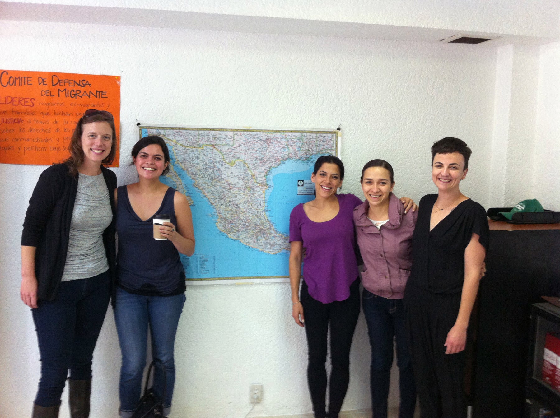 Five people posing in front of a map