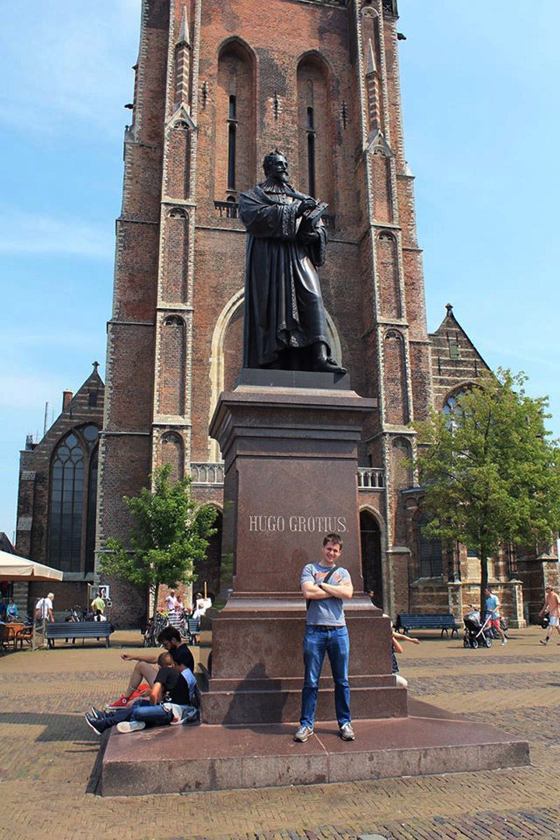 A man posing in front of a statue