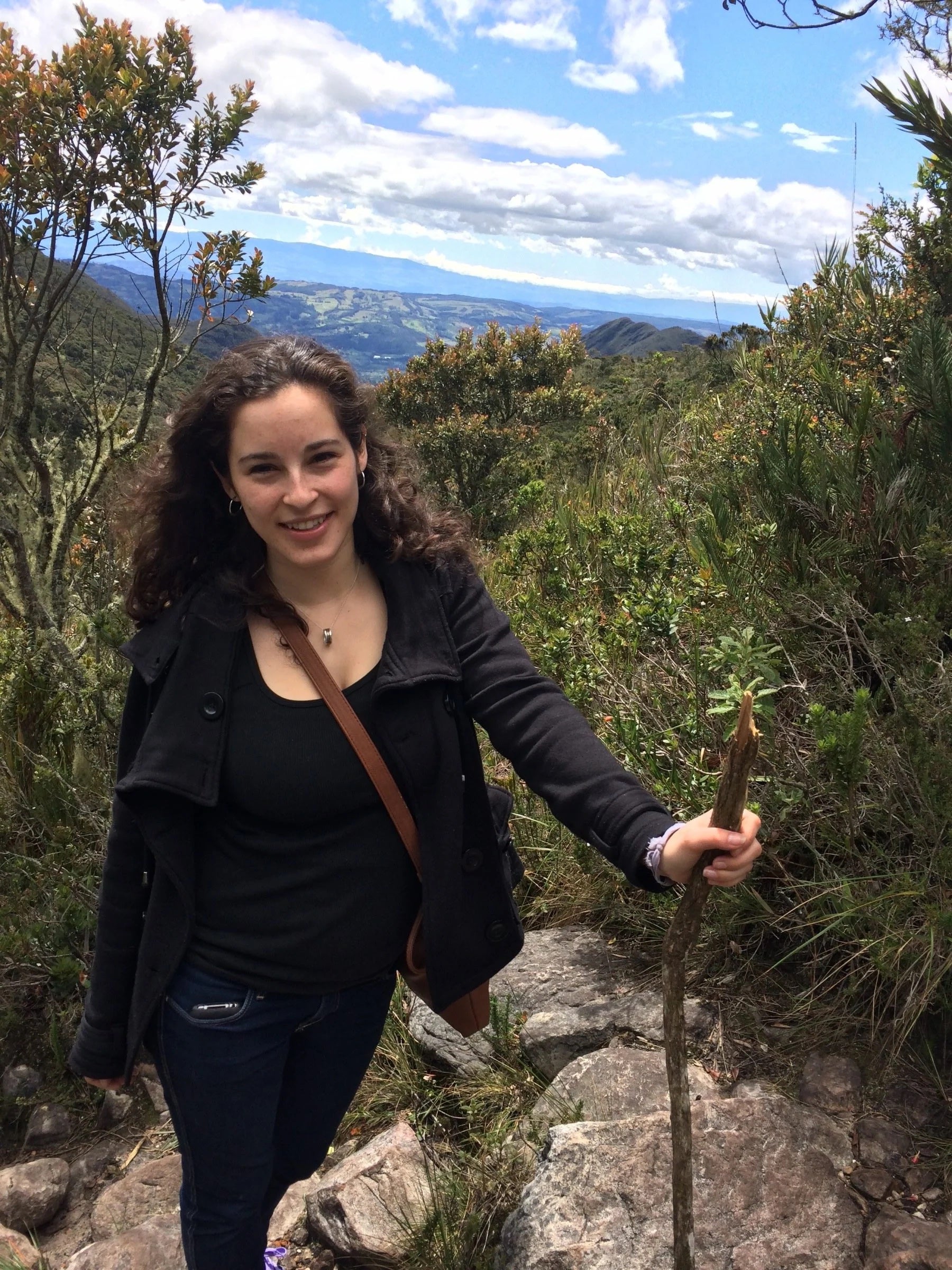 A woman posing with a walking stick in the forest