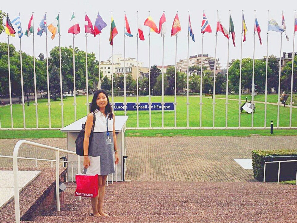 A woman posing in front of the flags of several countries