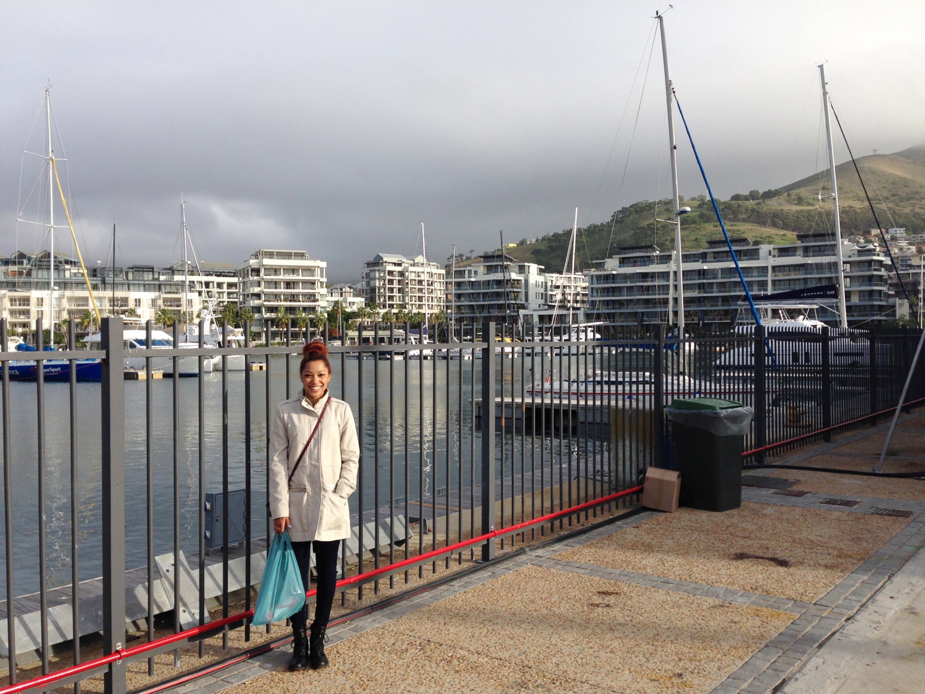 A woman posing in front of a fence in a harbor
