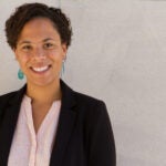 Tori Anderson in a black blazer and green earrings.