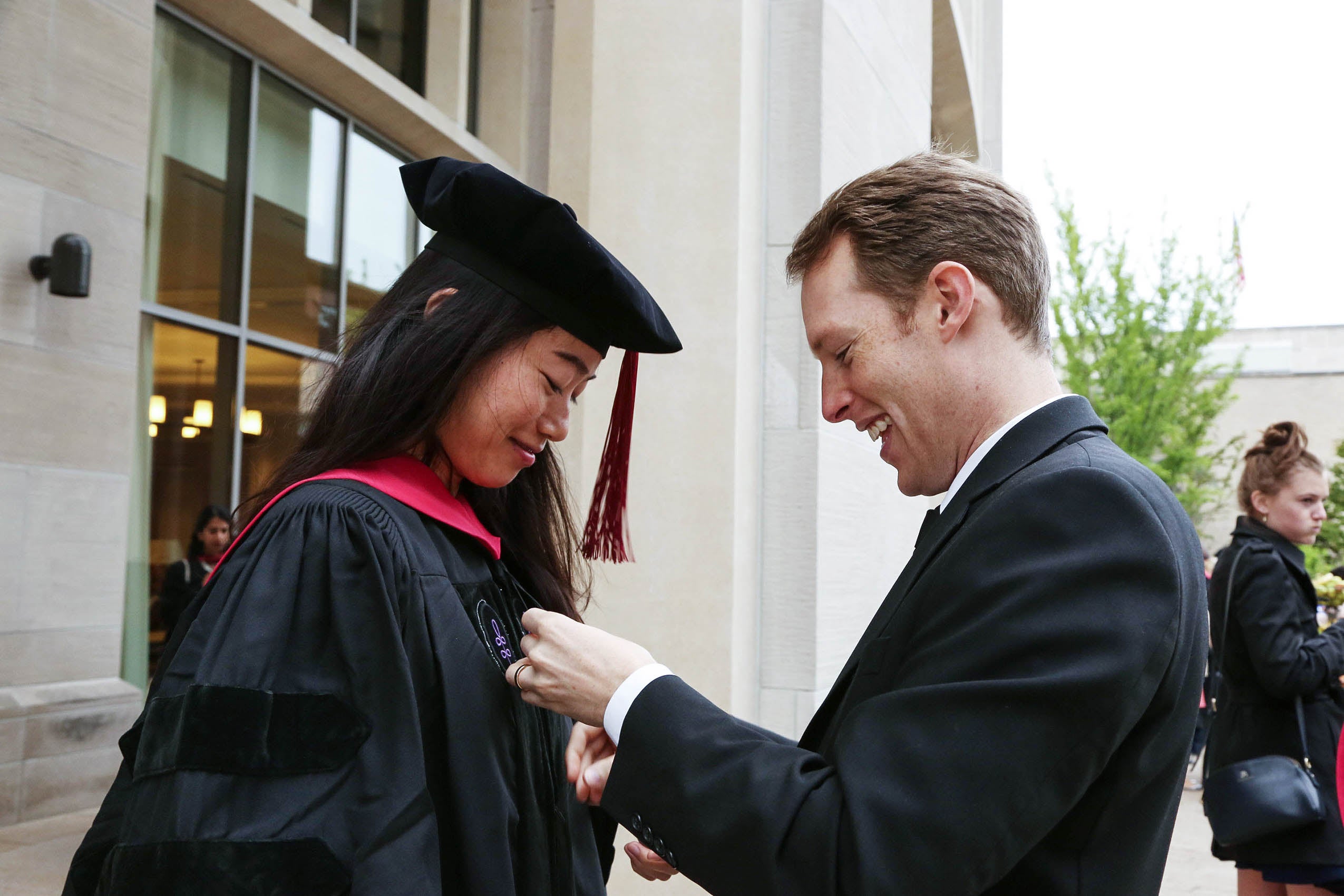 Pinning a badge onto a student wearing graduation robes