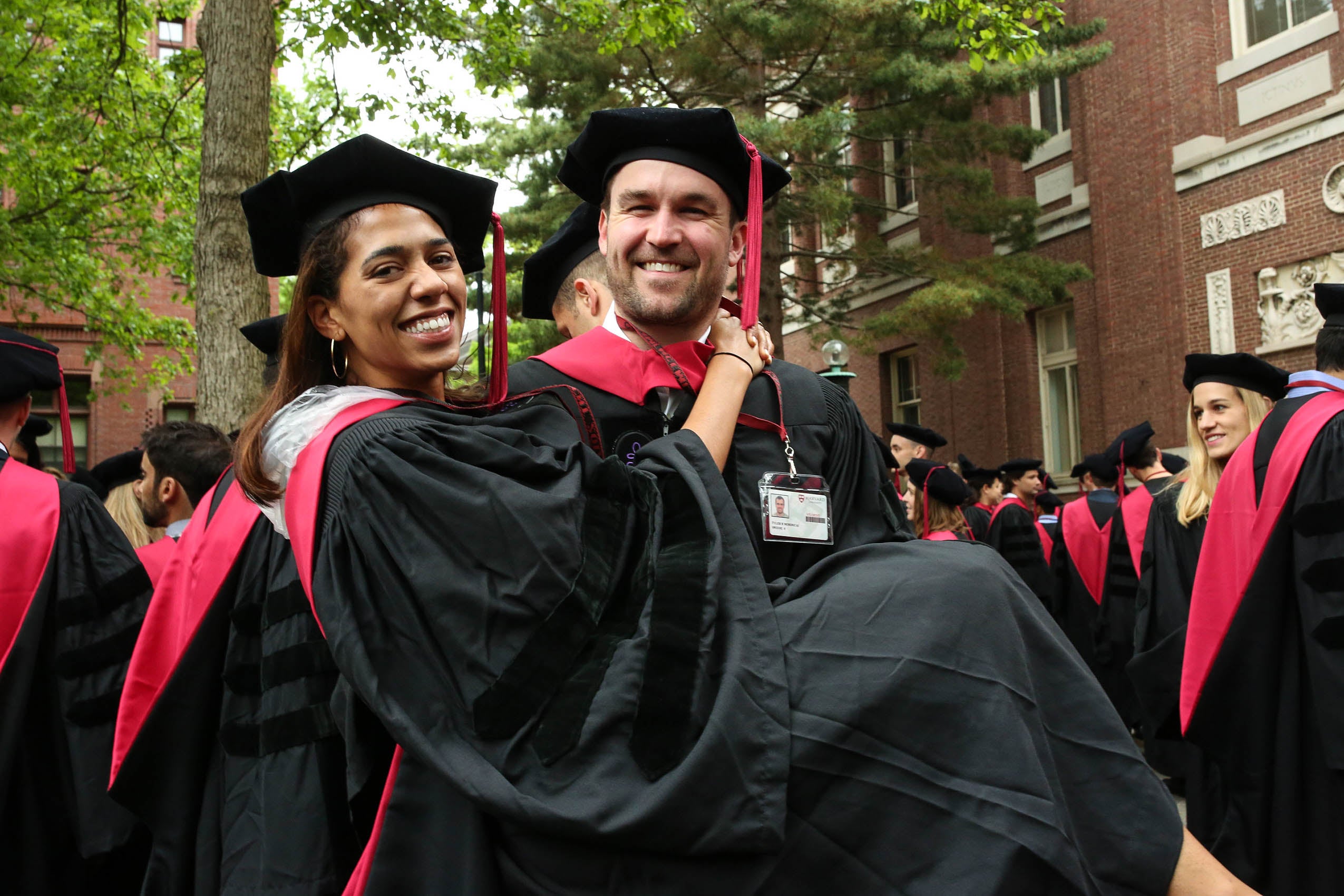 A man carrying a woman bridal style, both in caps and gowns