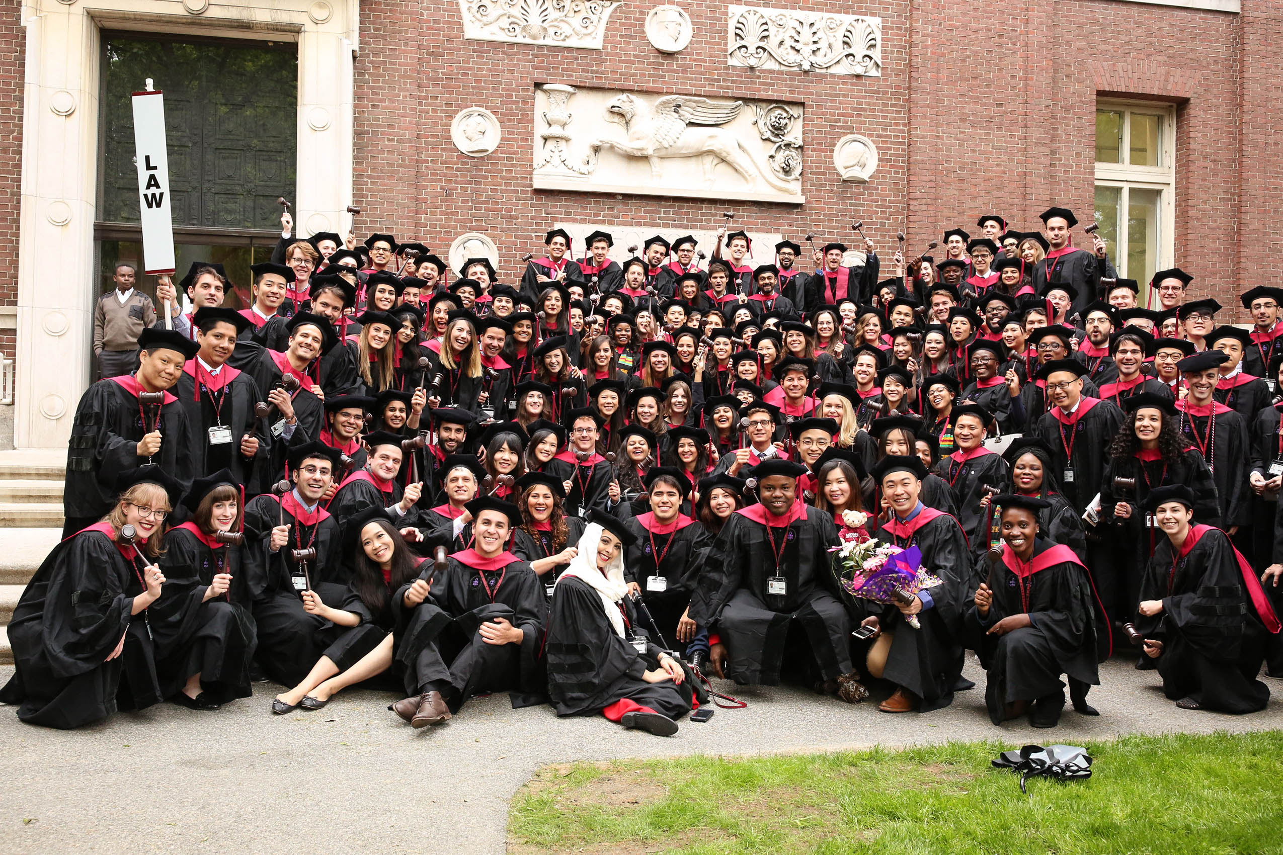 A large group of law students in caps and gowns, smiling