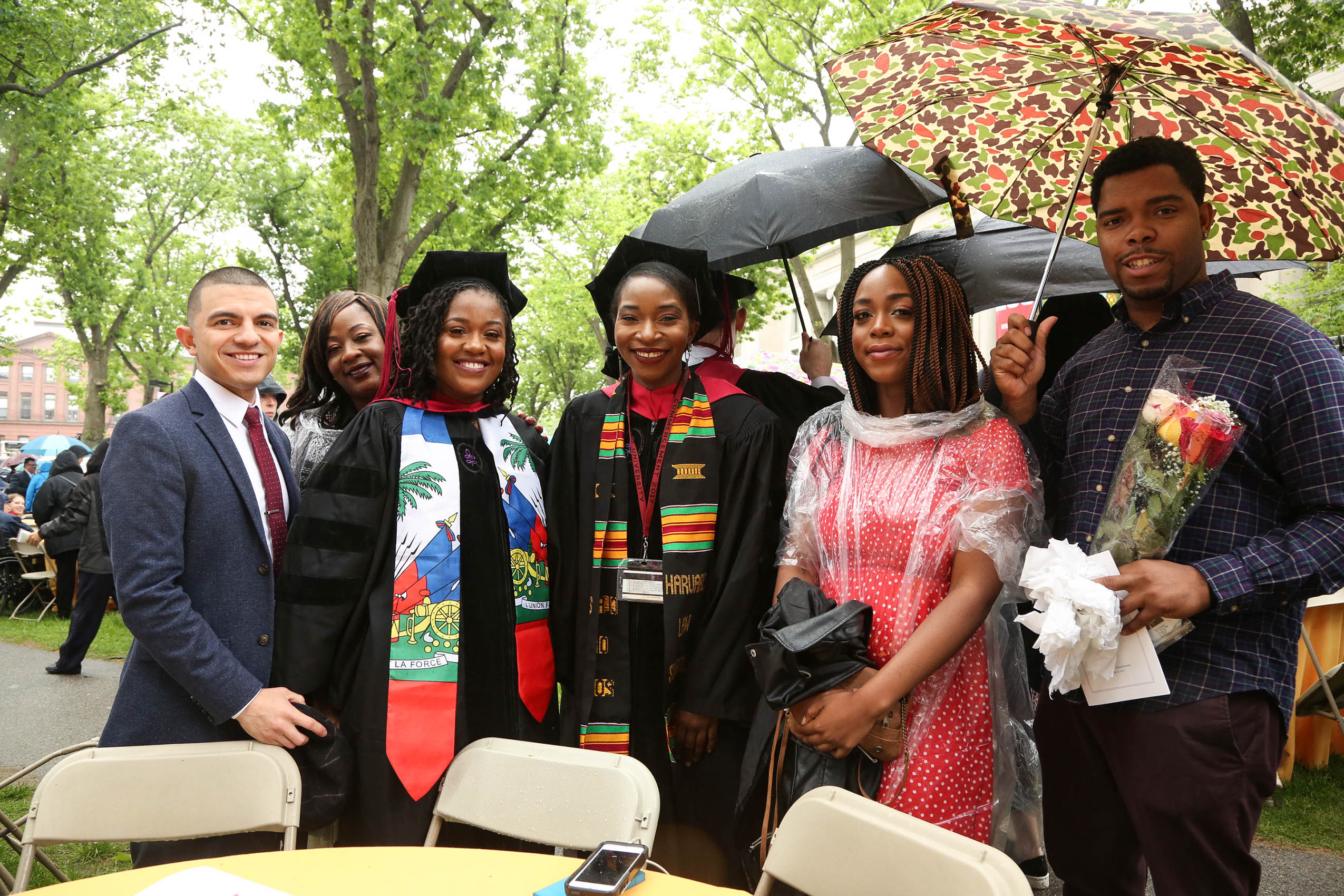 A group of four women and two men, smiling and standing on Holmes Field