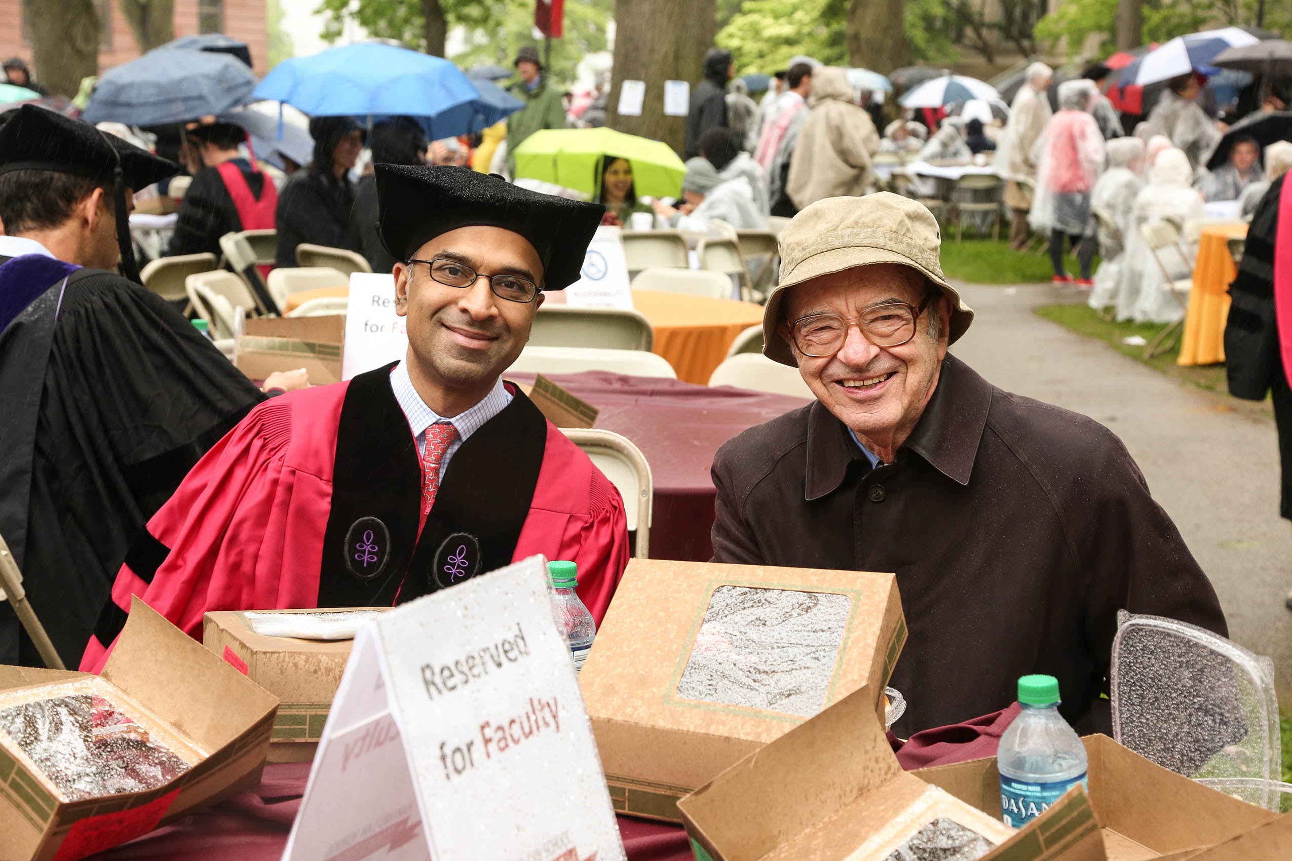Two men sitting at a table on Holmes Field, smiling