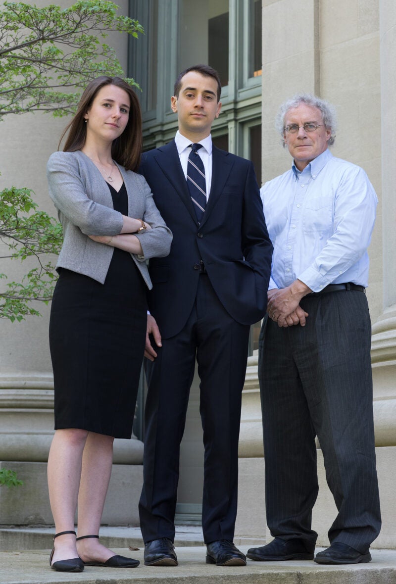 A younger man and younger woman posing with an older man on the courthouse steps