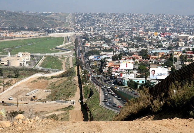 U.S. - Mexico border, showing buildings, structures, and cities on both sides.