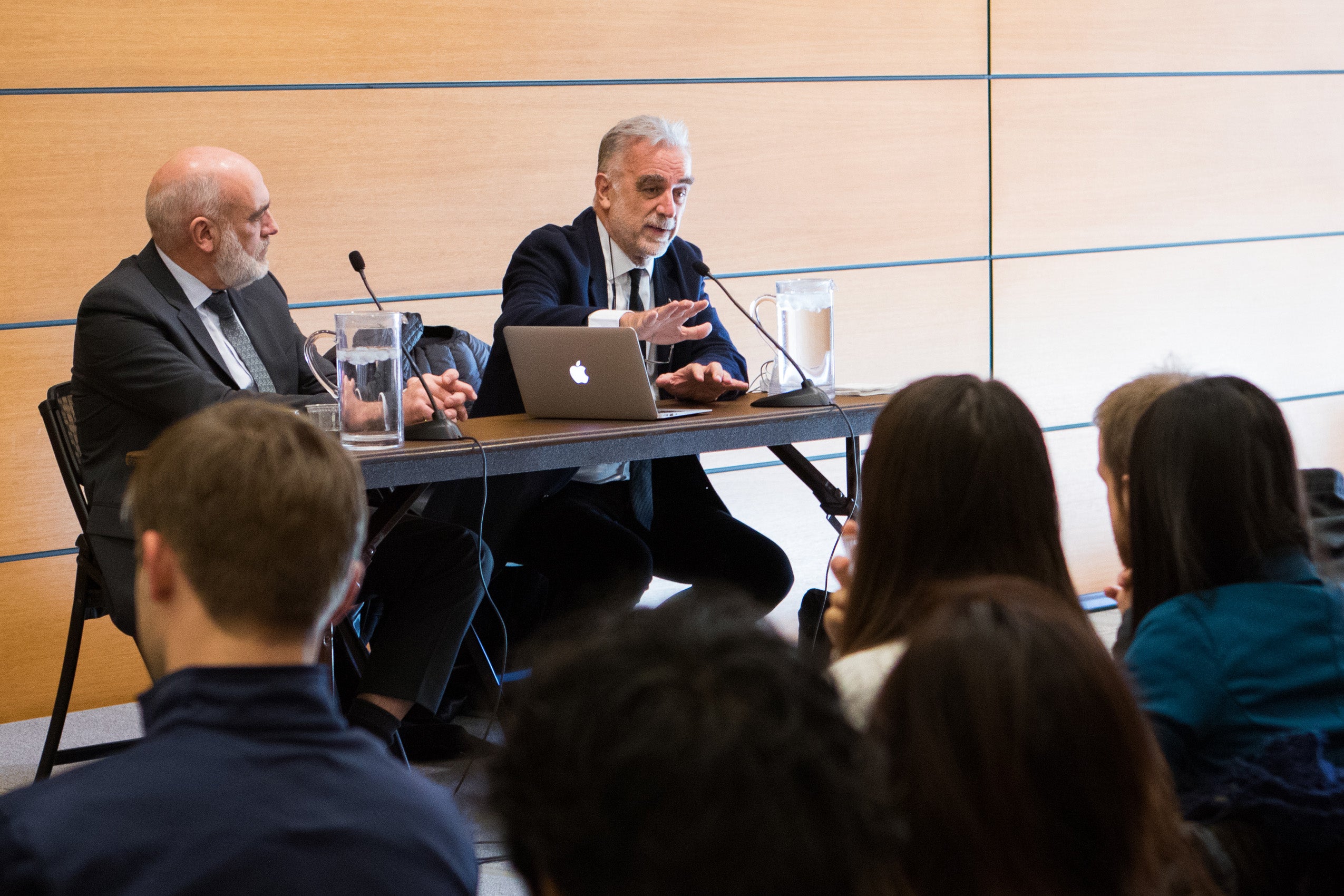 Luis Moreno-Ocampo and Tim McCormack speaking at a table with microphones, in front of an audience