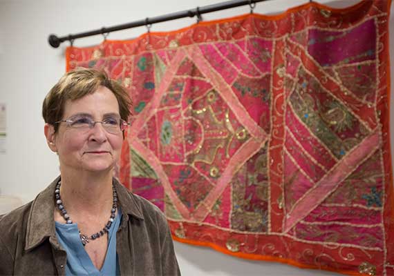 Deborah Anker posing beside a hanging tapestry