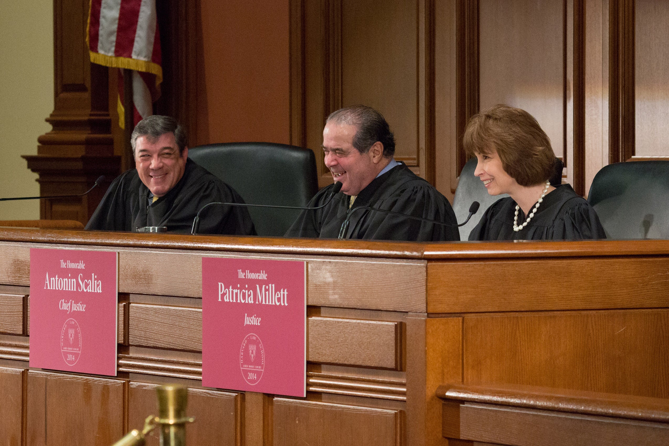 Three justices smiling behind the bench