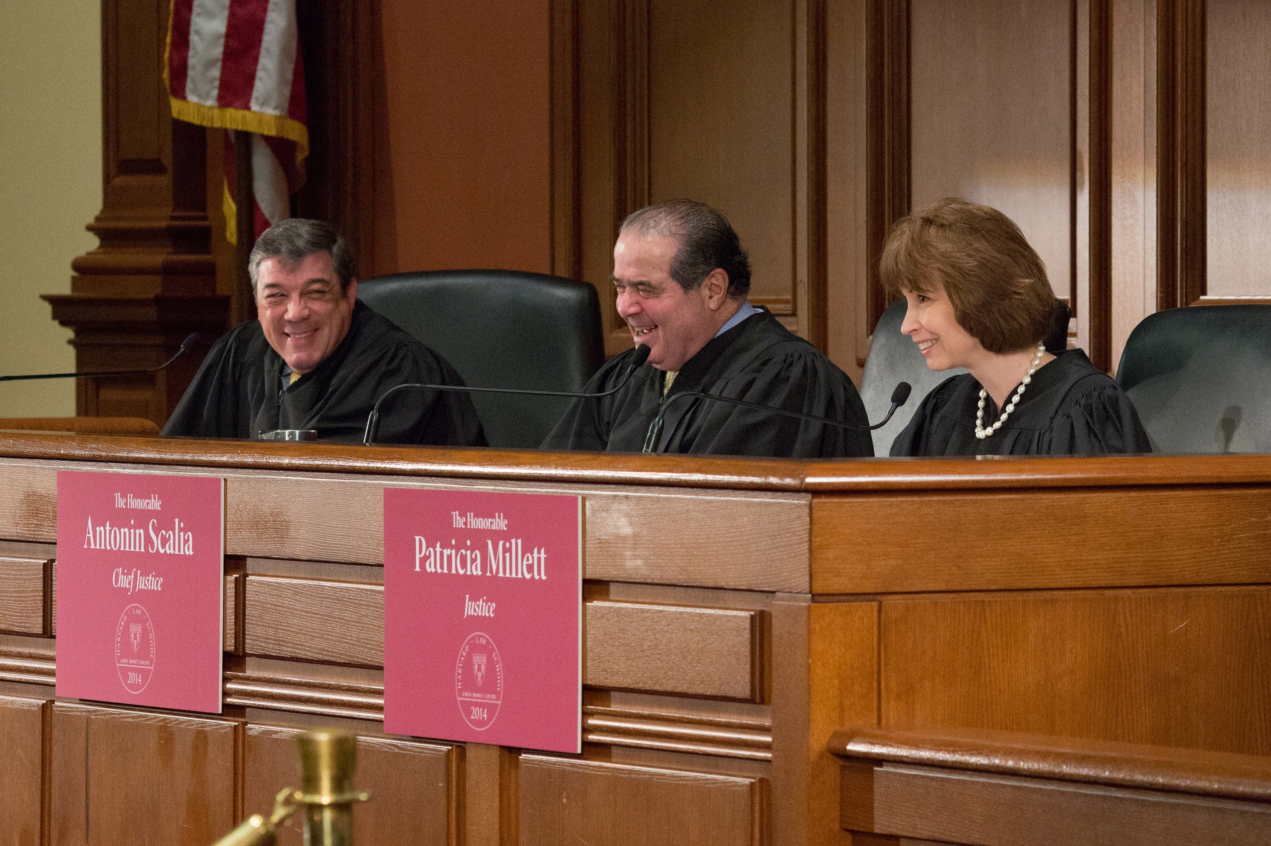 Justice Antonin Scalia with two other justices laughing behind the desk