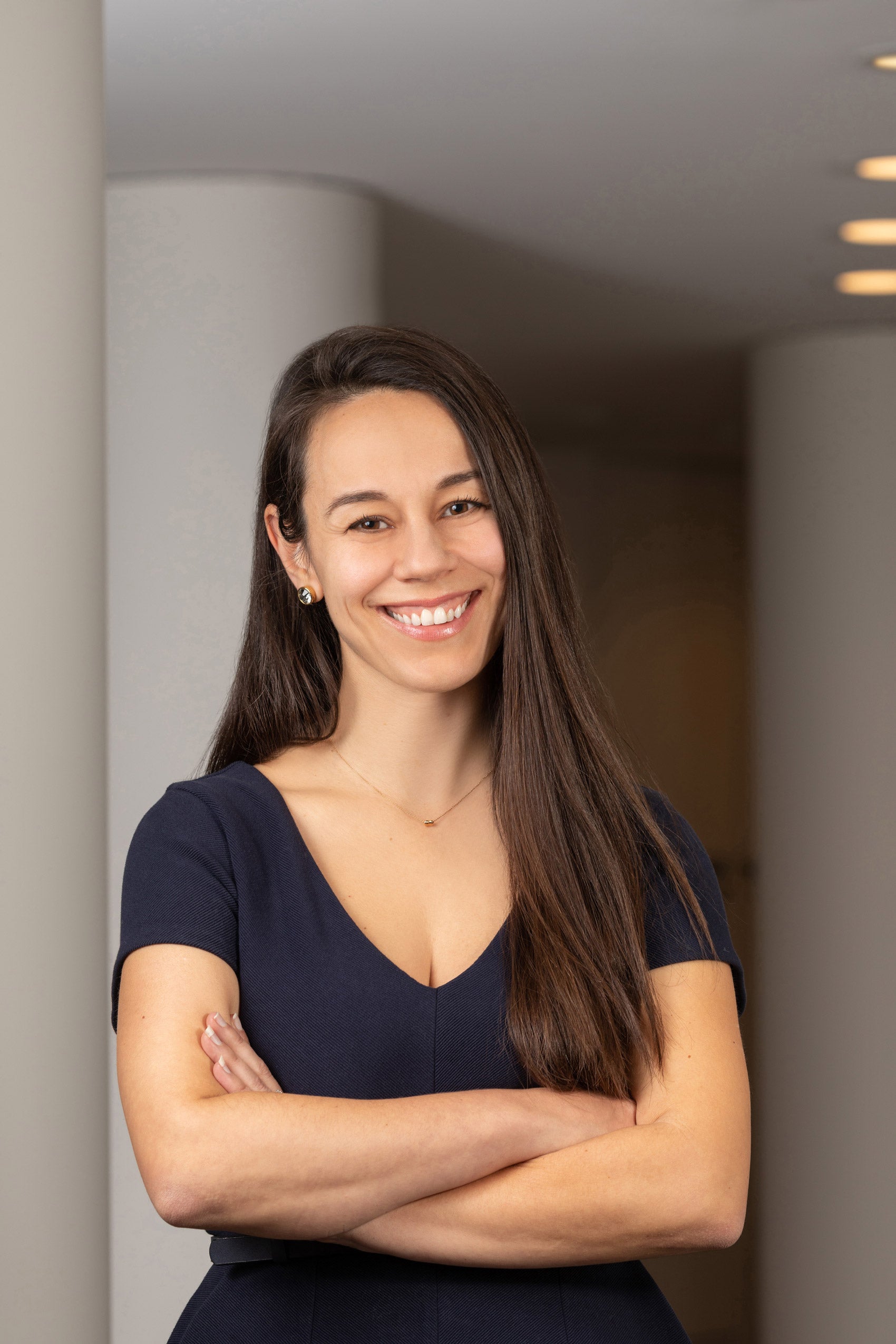 Woman smiling standing in doorway outside with arms crossed