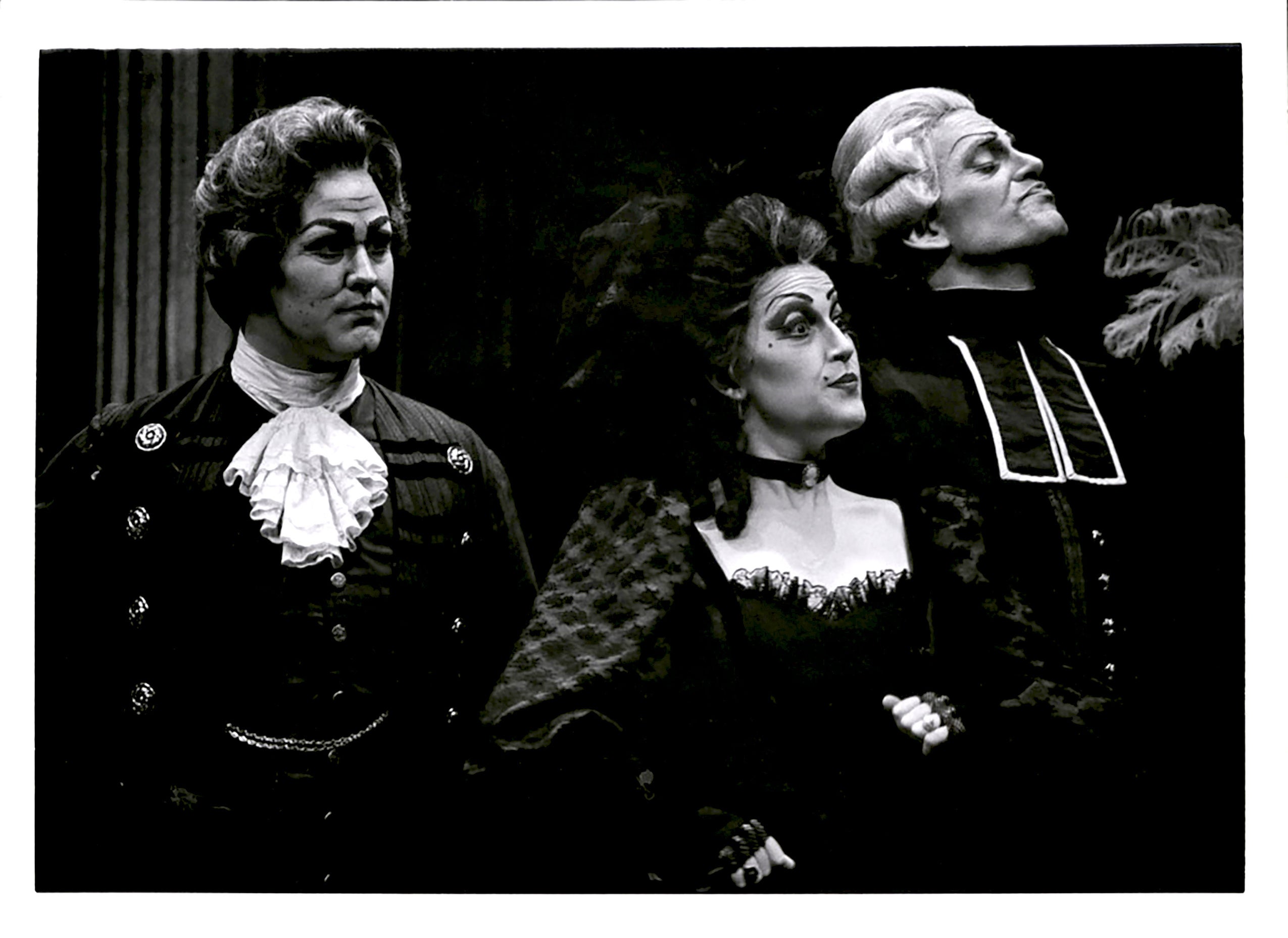 Three actors wearing costumes performing on a stage
