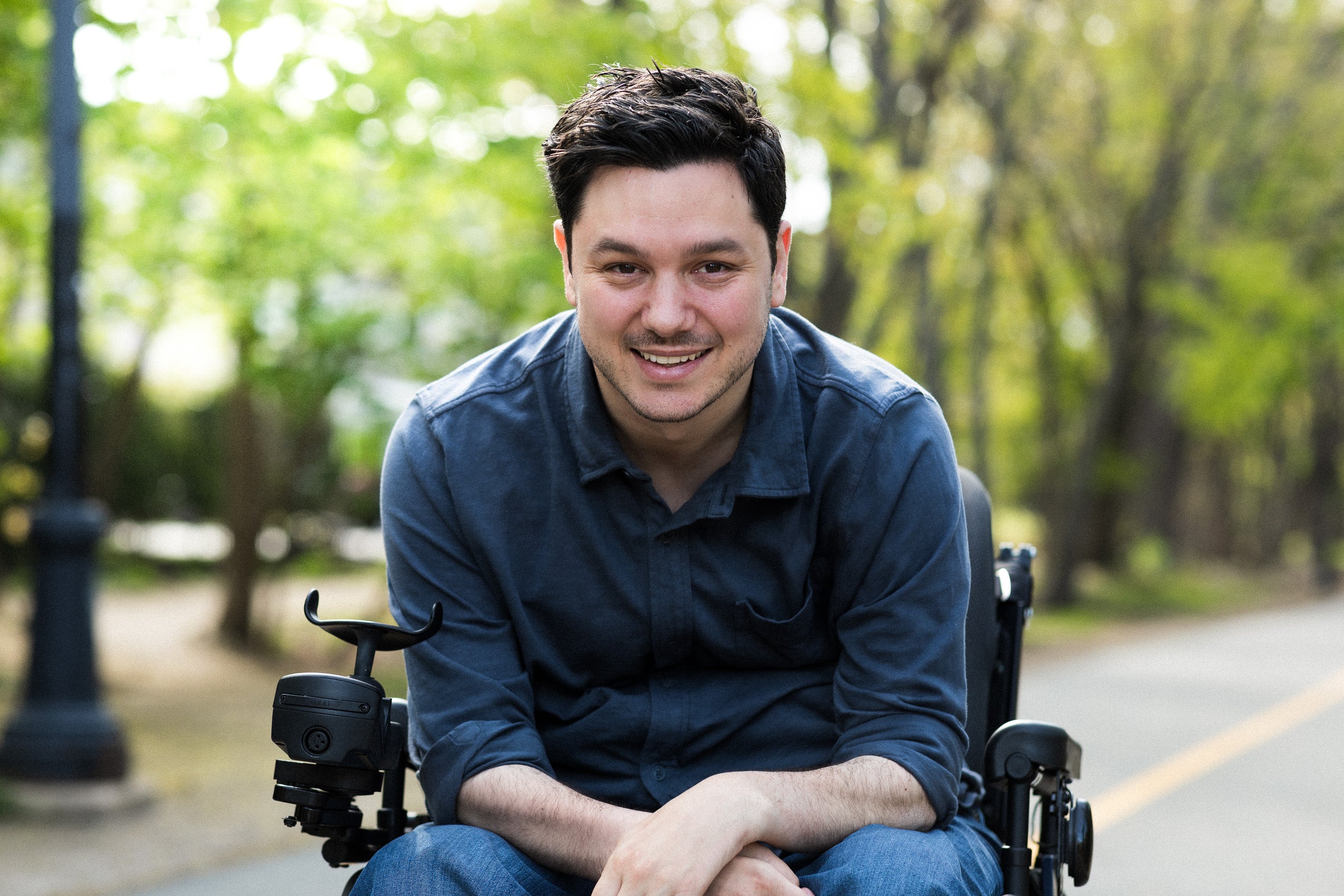 man wearing a blue shirt and jeans sitting in a wheel chair