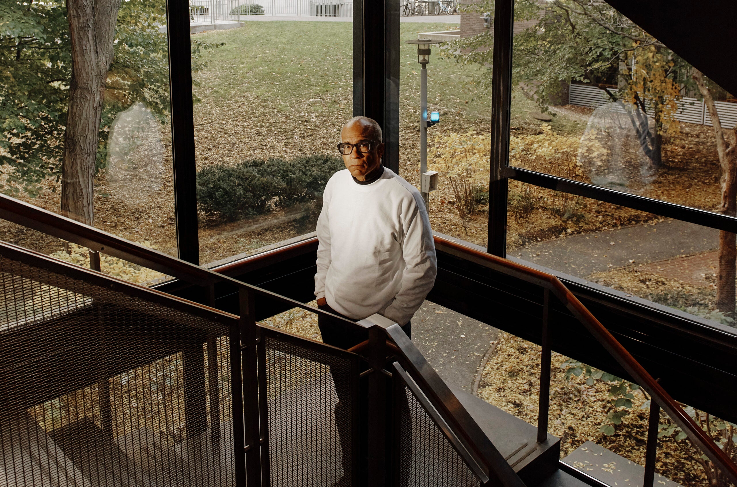 Man standing in stairwell of Griswold Hall, with view of campus behind him