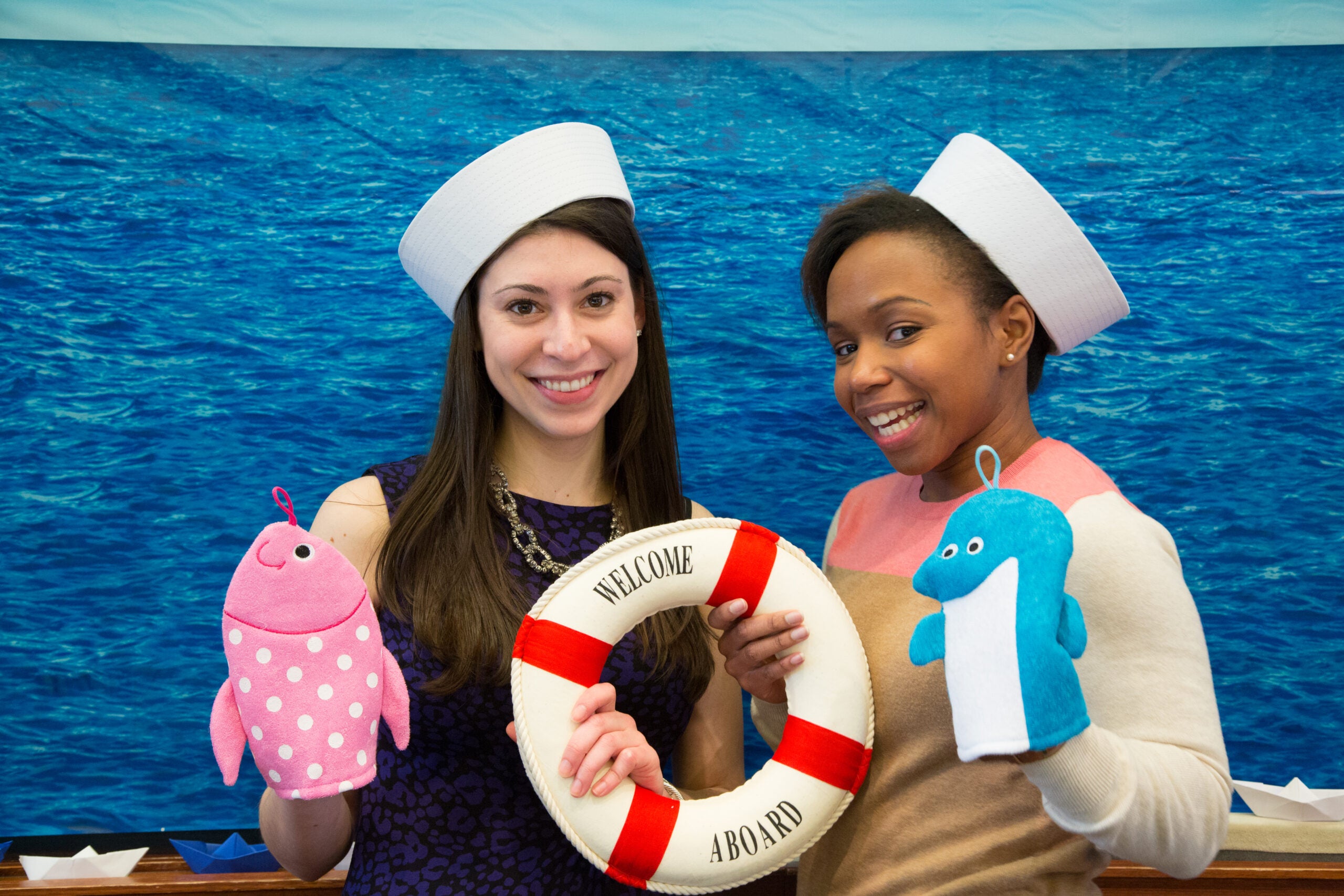 Two women posing together with marine life puppets, sailor hats, and a life preserver