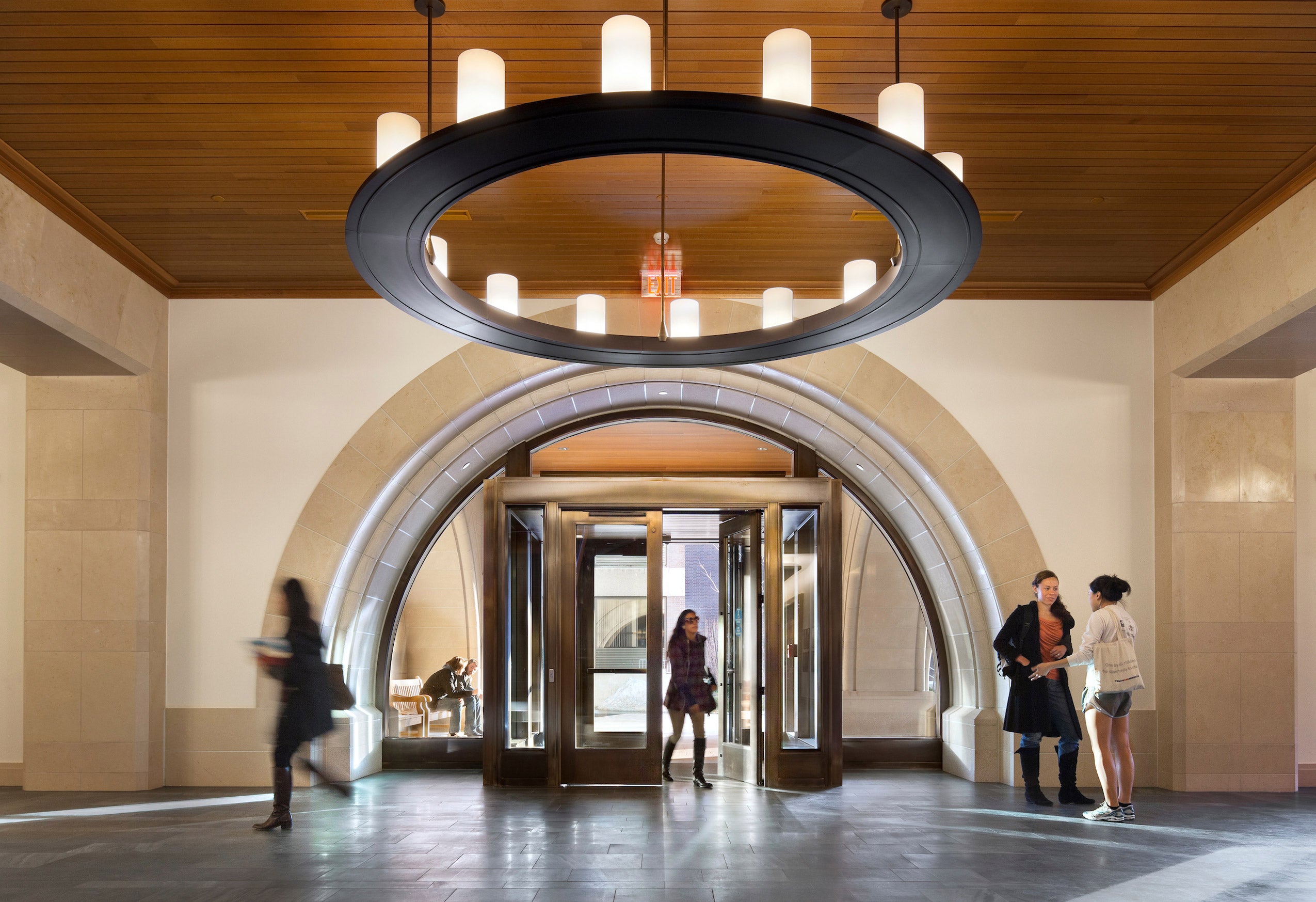 Interior shot of the entranceway to the Wasserstein building. Students entering the doorway and talking in the lobby.