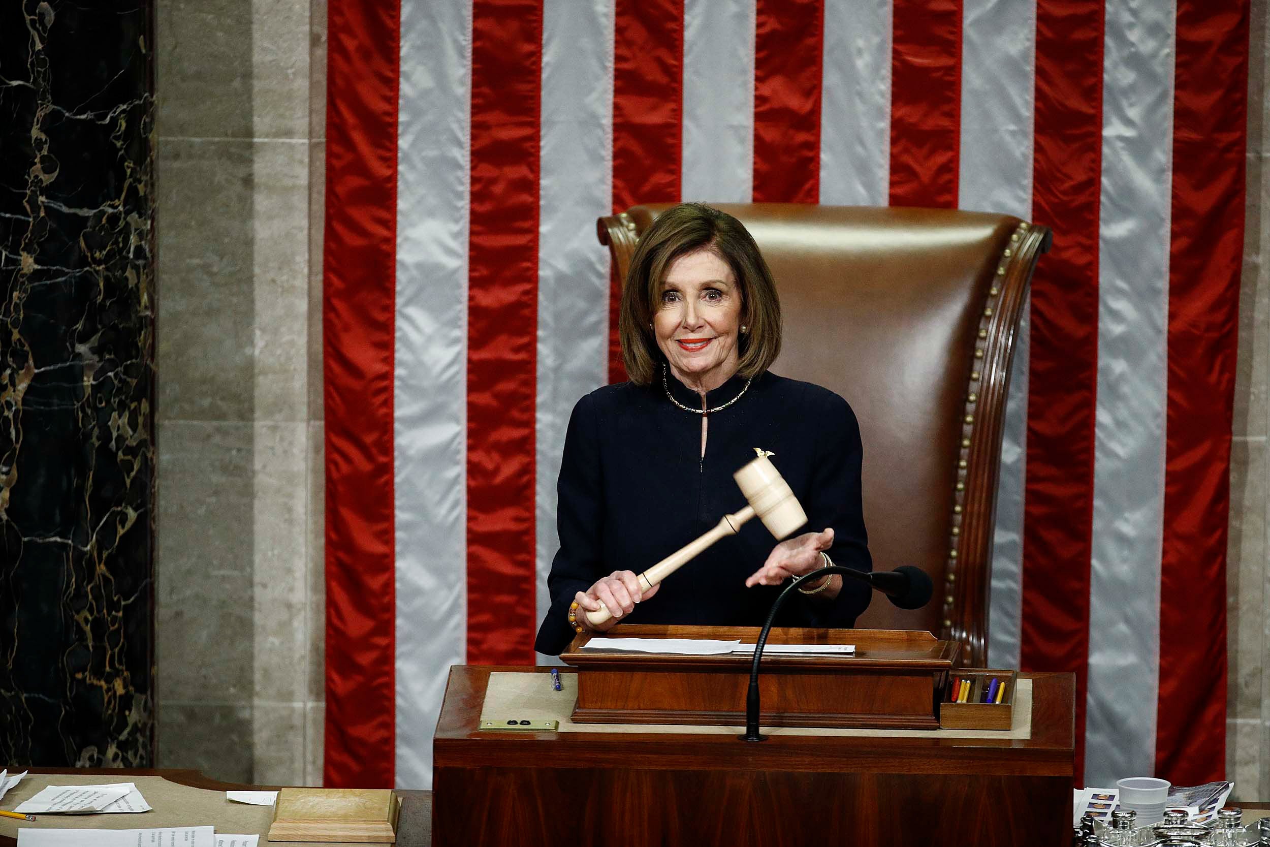 Nancy Pelosi stands holding the gavel during impeachment vote against President Trump.