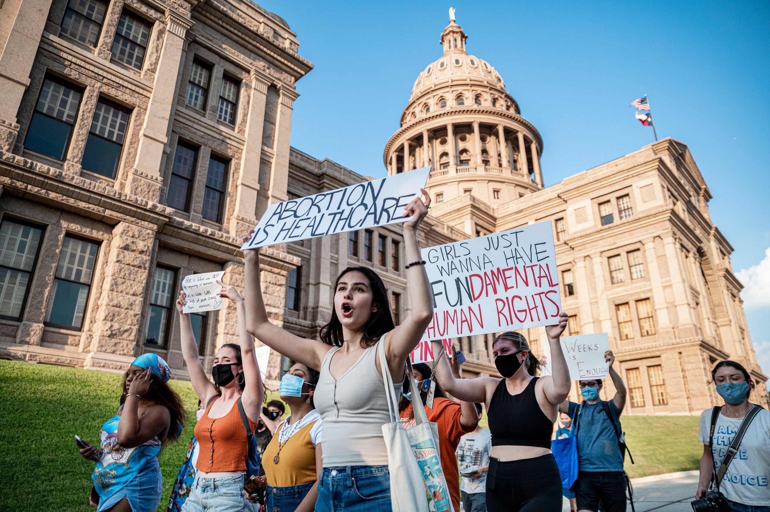 Female protesters holding signs march outside the Texas State Capitol