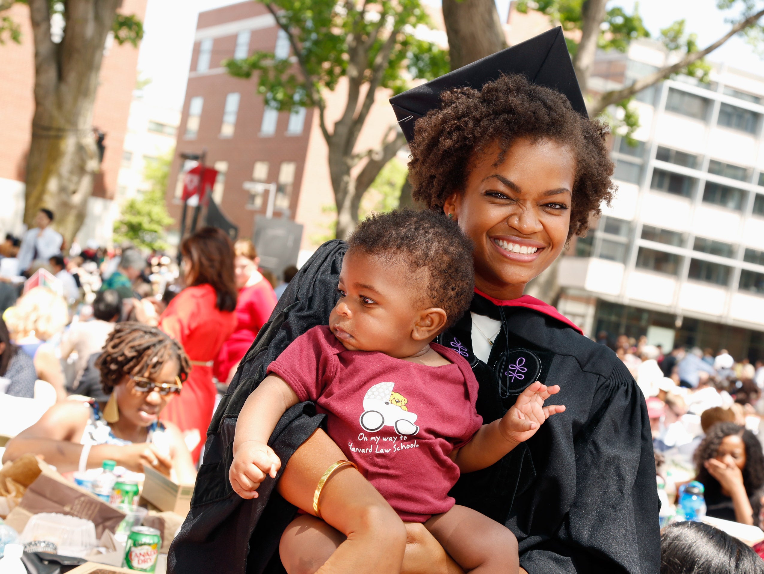 A graduate smiling and holding a baby