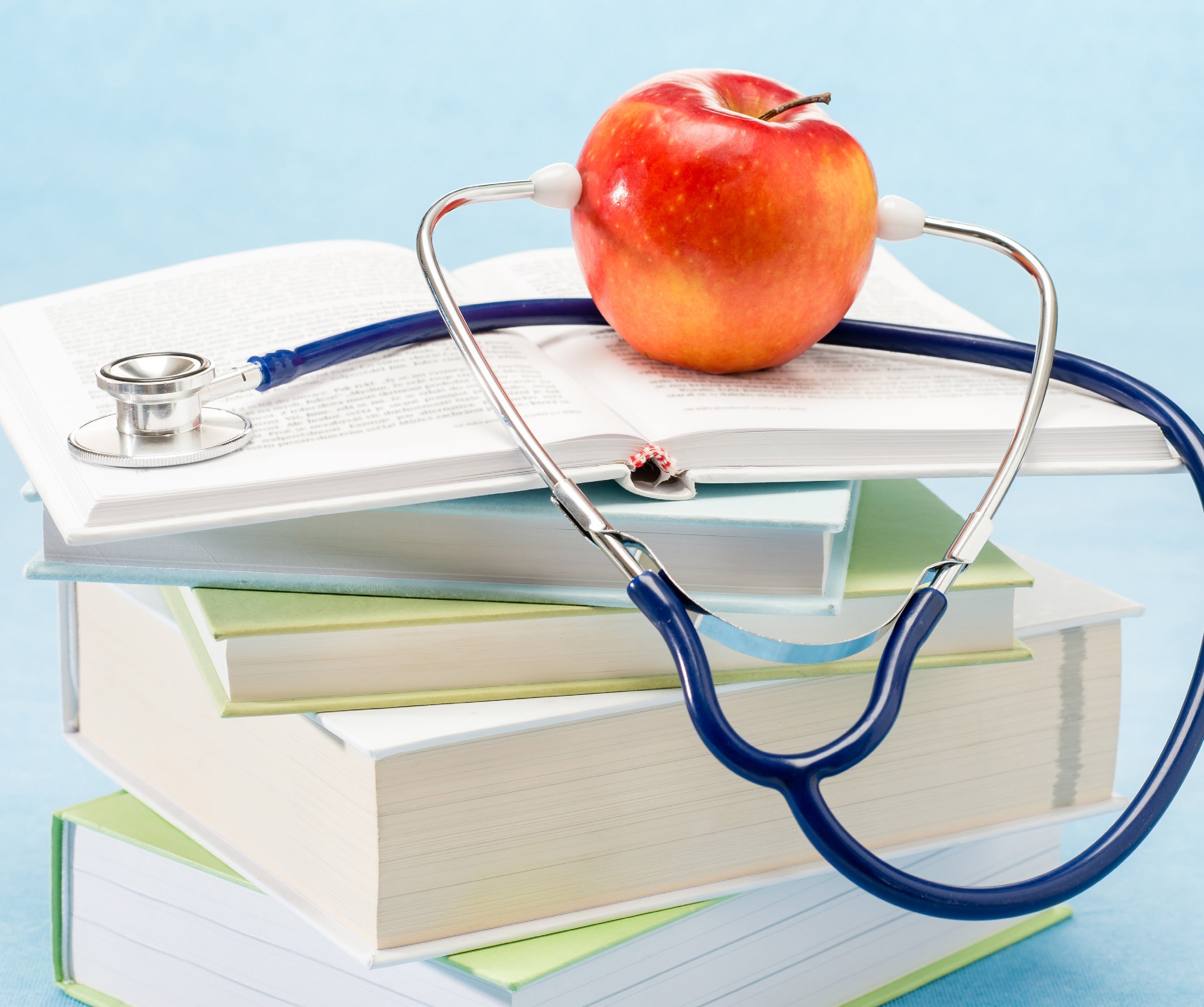 An apple with a stethoscope, on top of a stack of books