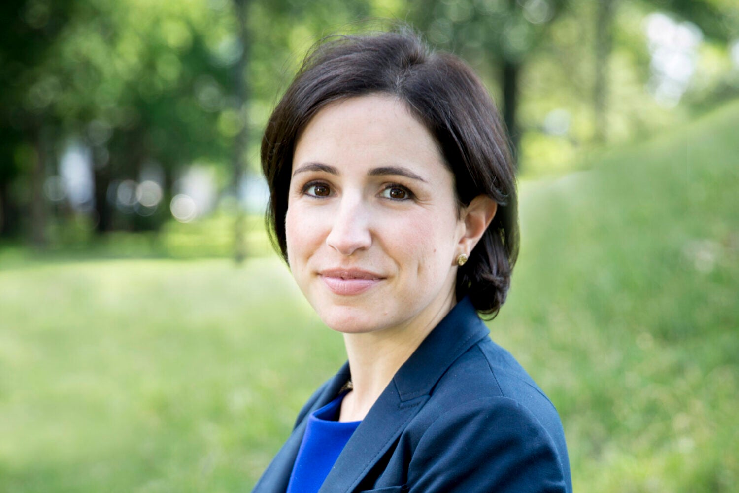 photo of Emily Broad Leib sitting on a rock bench in front of a grass lawn