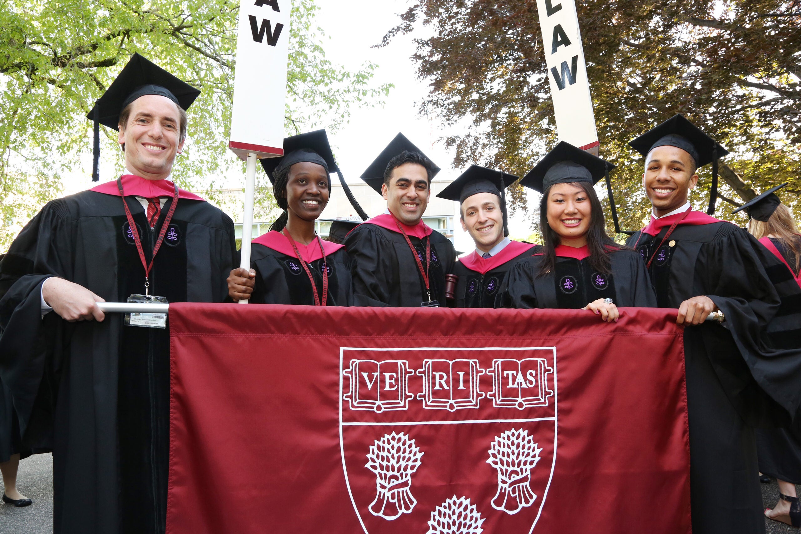 A group of graduates holding a banner with the HLS shield on it