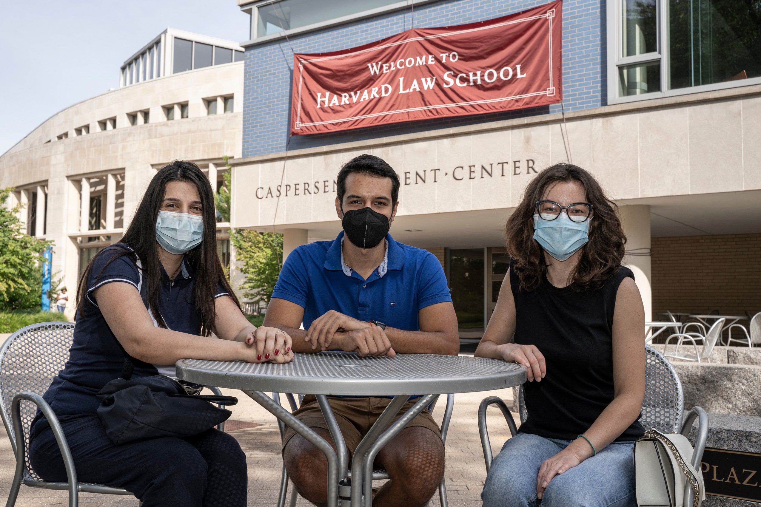 Three students sitting at a table outside on Harvard Law School campus