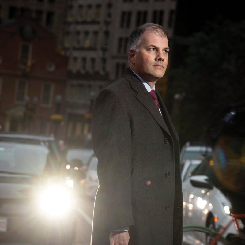 Mark Fleming '97 standing in a crosswalk with cars behind him