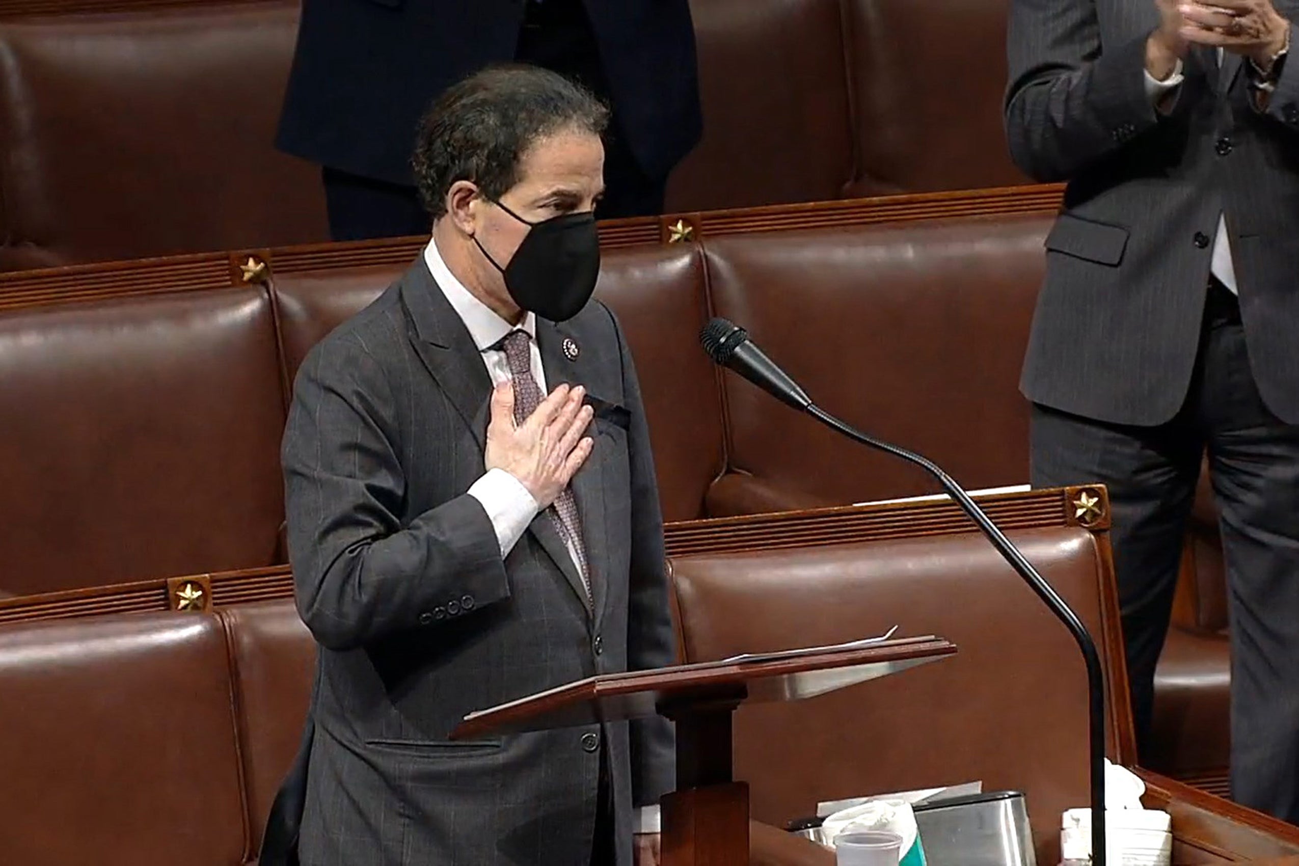 Jamie Raskin wearing a black mask hold his hand over his heart