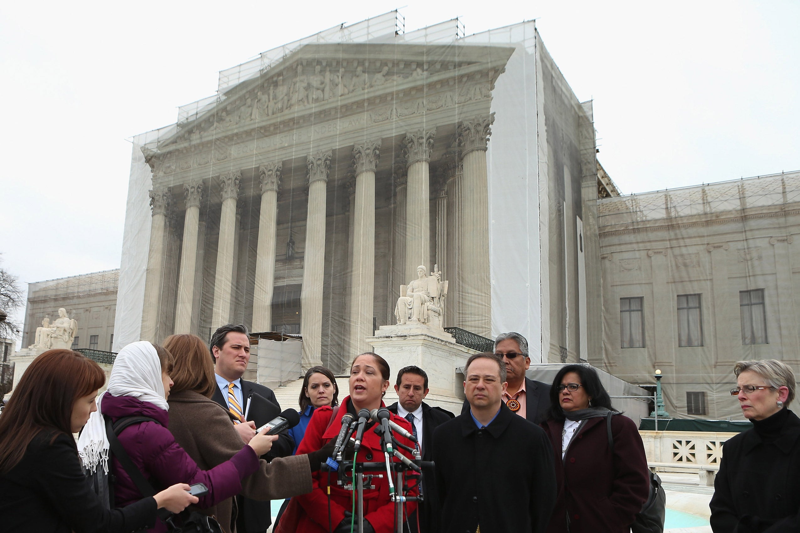 A woman stands in front of microphones talking to reporters in front of the U.S. Supreme Court.