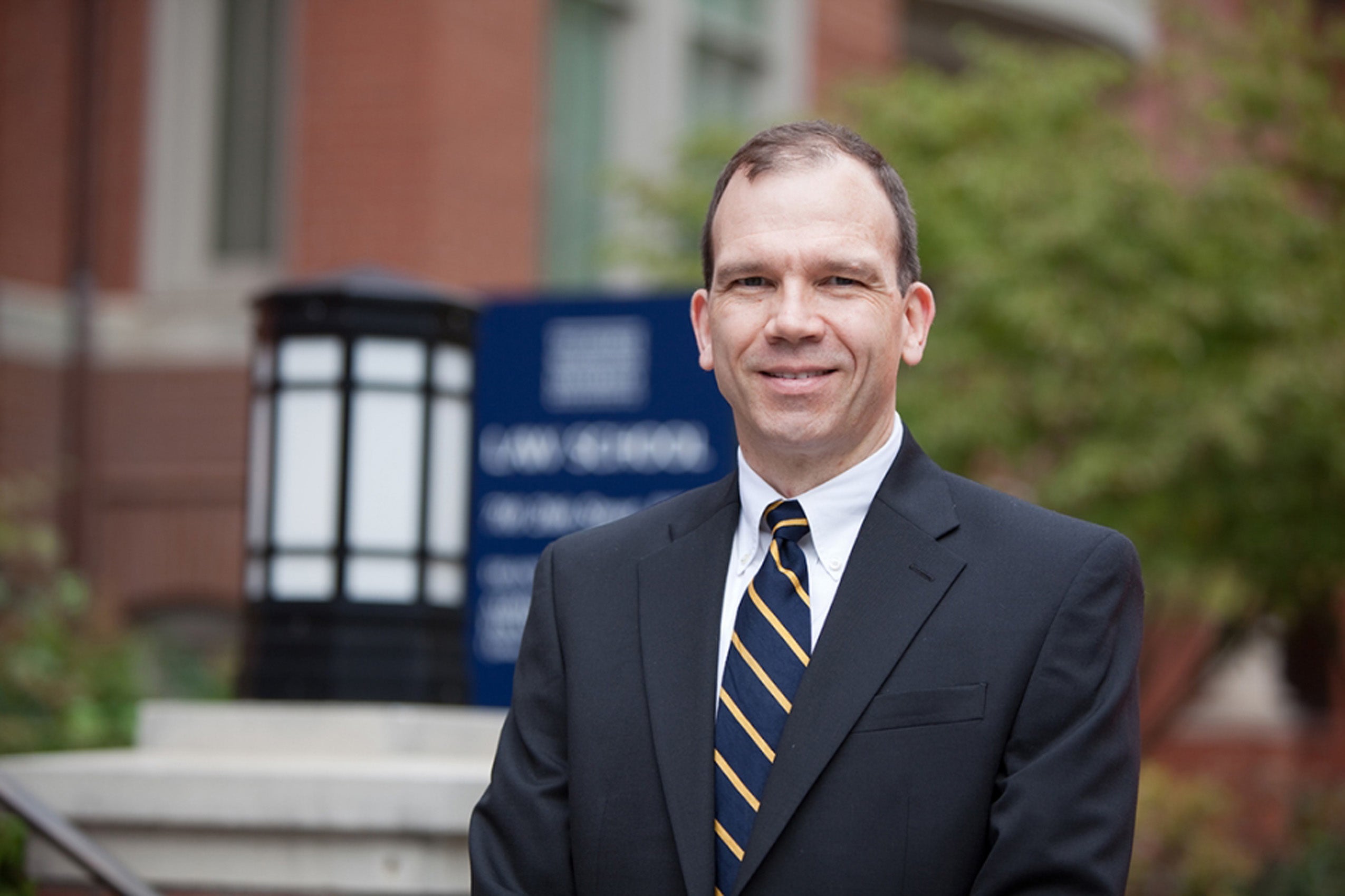 Man wearing a gray suit and tie standing outside