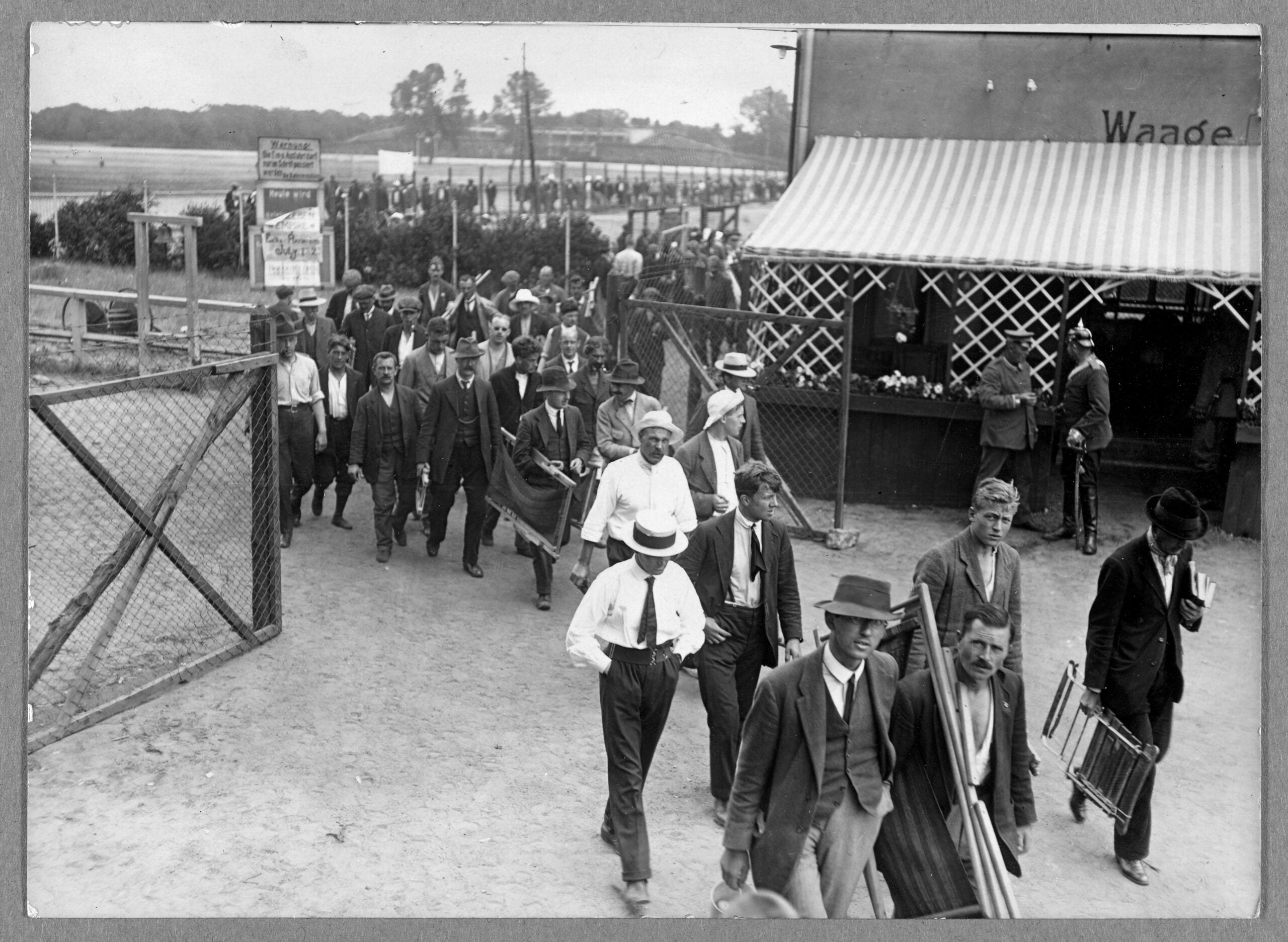 Men passing through a gate in a prison camp