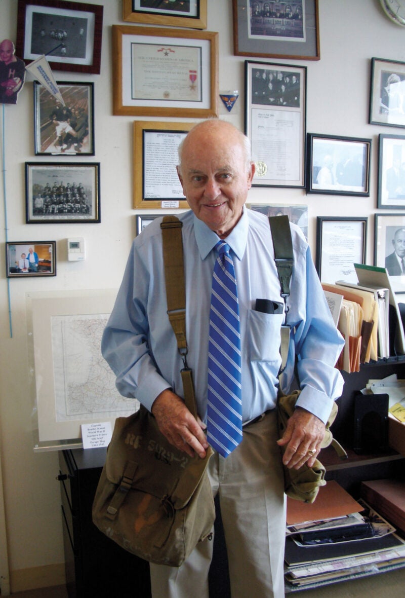 Man standing in a room with lots of pictures behind him on the wall