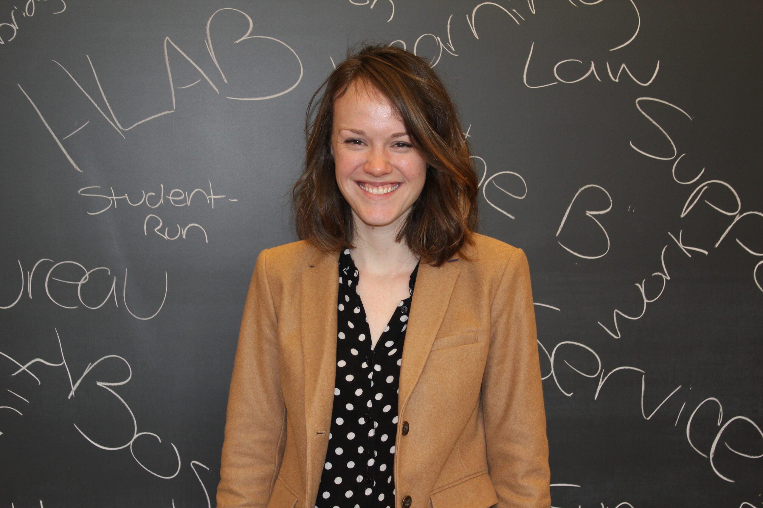 Lerae Kroon smiling in front of a chalkboard