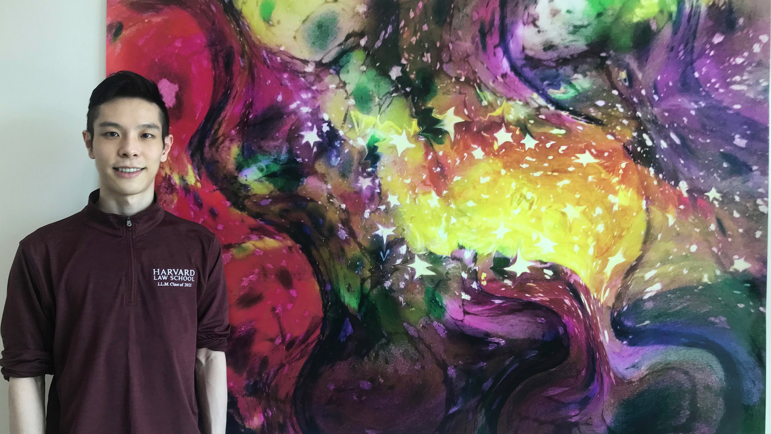 Man wearing crimson shirt in front of a colorful painting