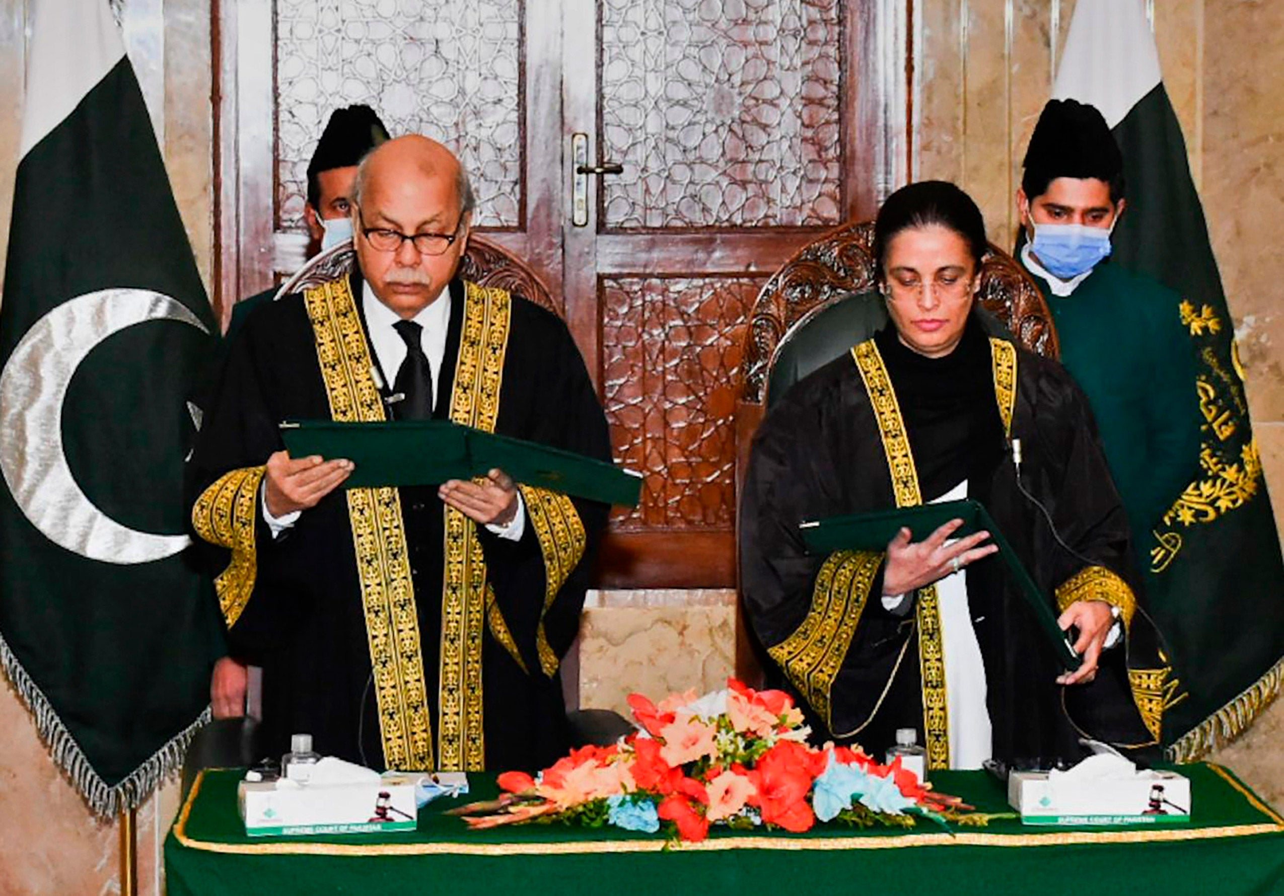 Man wearing Supreme Court of Pakistan robe and woman wearing Supreme court of Pakistan robe reading a document in a swearing in