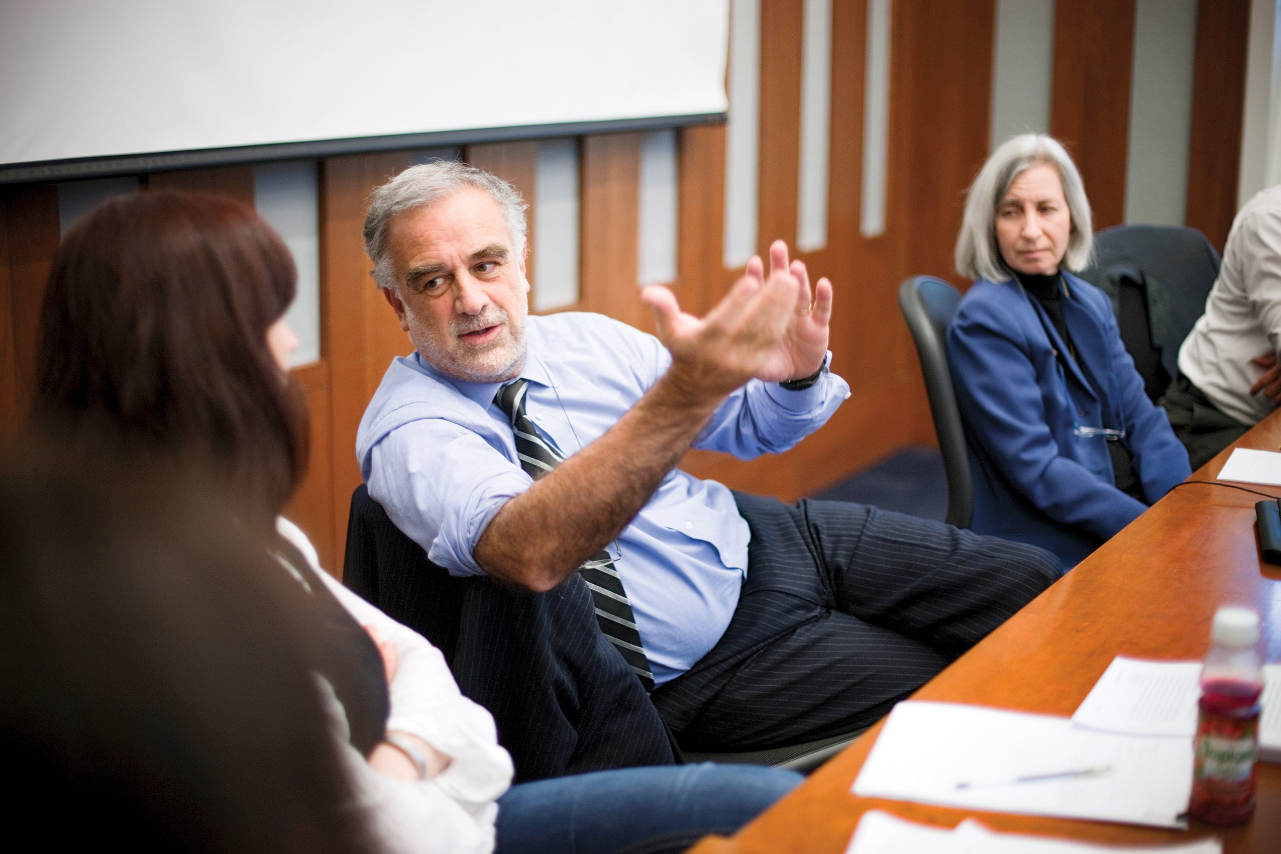 Luis Moreno-Ocampo sitting with colleagues and gesturing animatedly