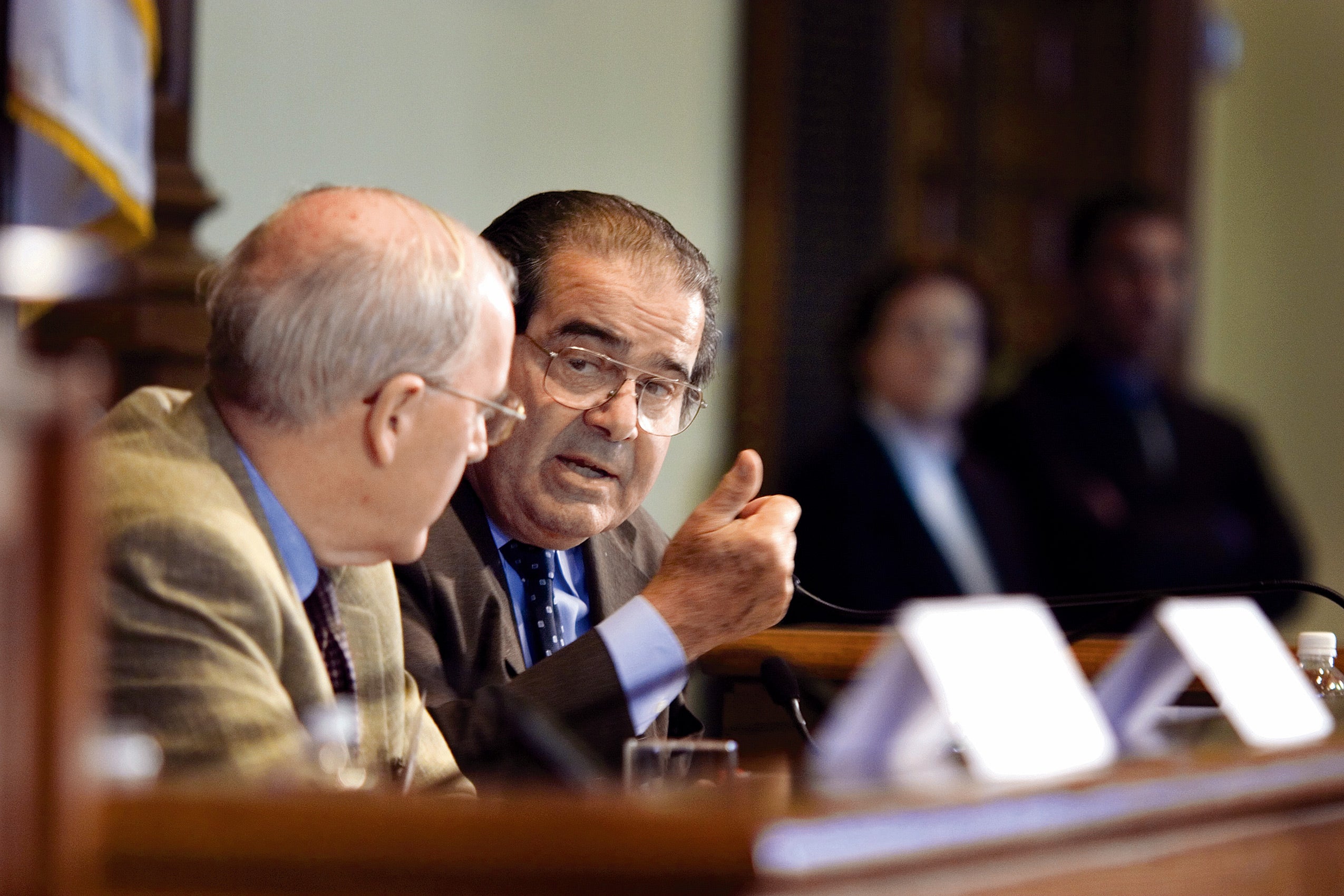 Justice Antonin Scalia on a panel speaking to another panelist behind a wooden desk