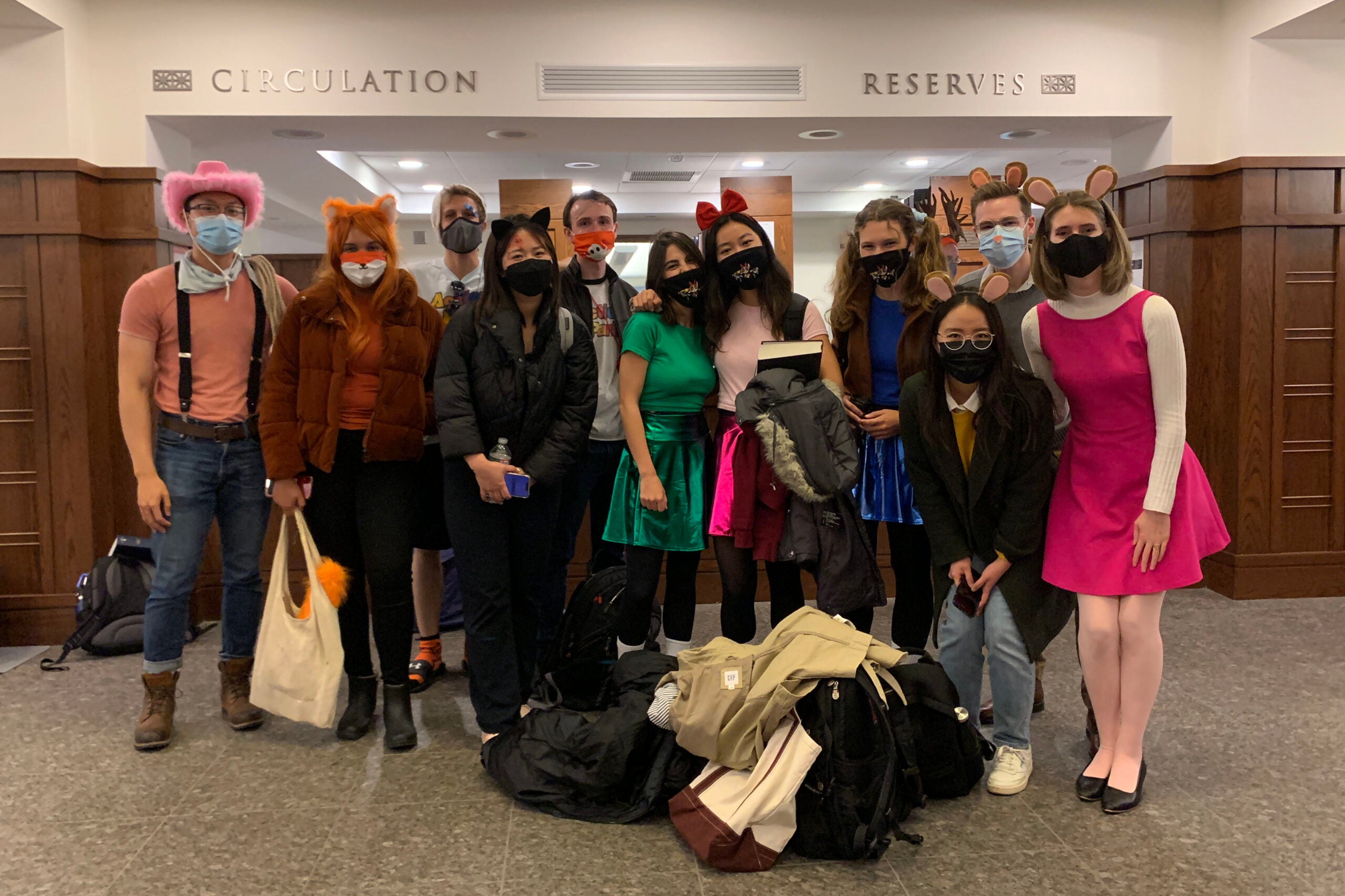 Group of students wearing face masks and wearing Halloween costumes posing for the camera.