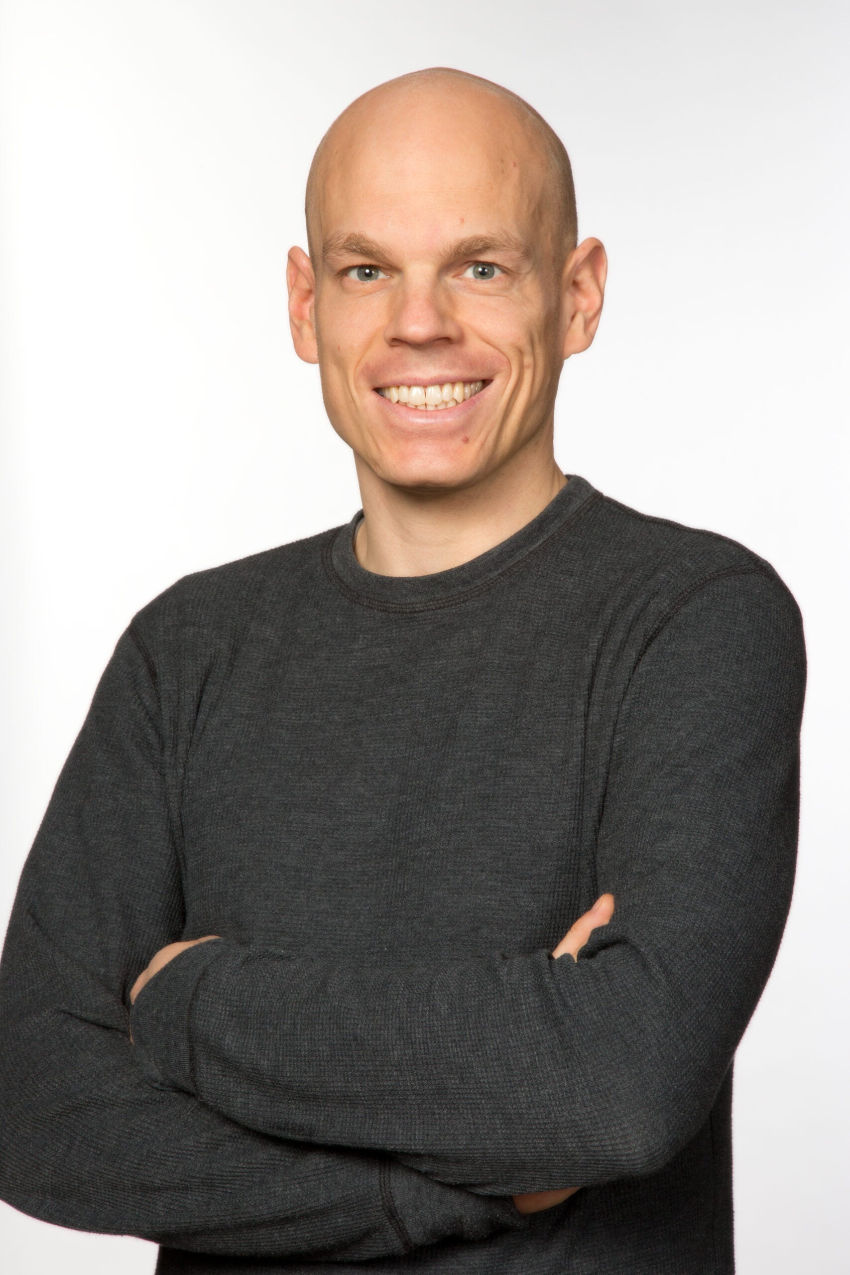 Holger Spamann smiling at the camera with arms folded in a longsleeve black shirt