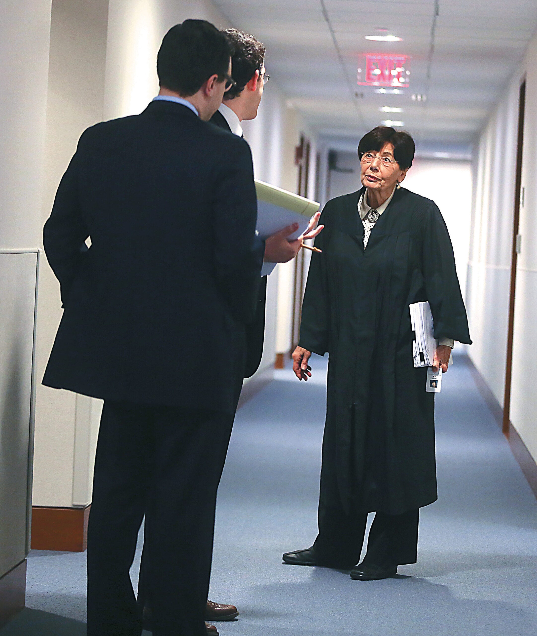 Rya Zobel in judges robes stands in the hallway of the court with her law clerks