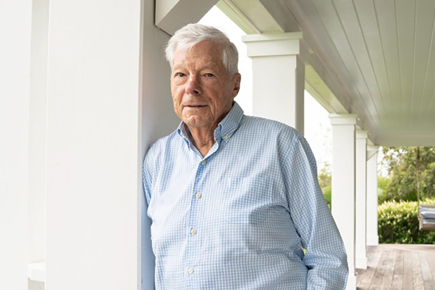 Man outside of a house leaning against a pillar