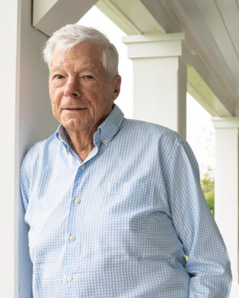 Man outside of a house leaning against a pillar