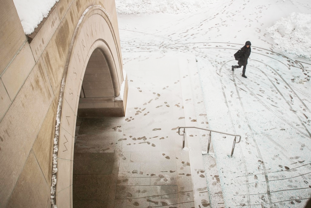 Top view of a student walking across a snowy campus filled with footprints in the snow