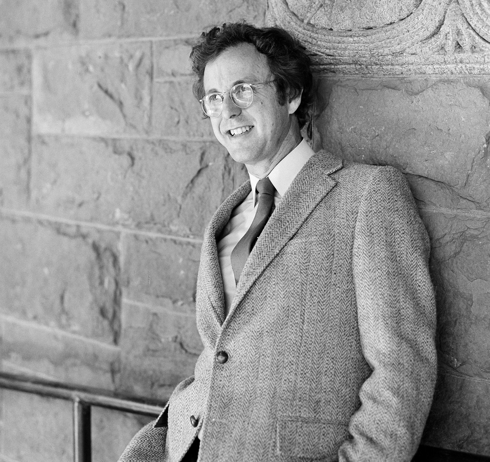 black and white portrait of man leaning against a Harvard Law building
